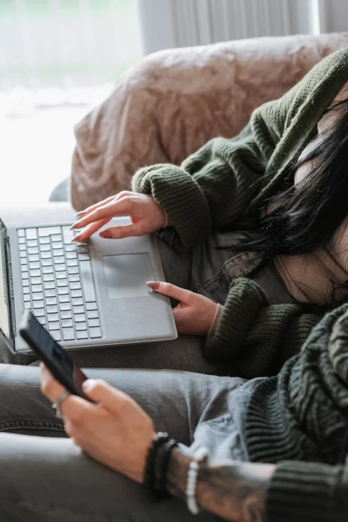 Femme assise sur le canapé avec son ordinateur sur ses genoux